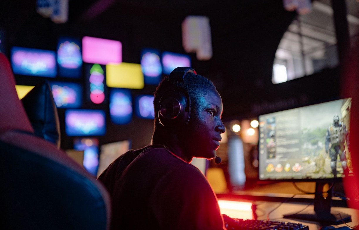 A gamer with a headset competing at a PC under neon light