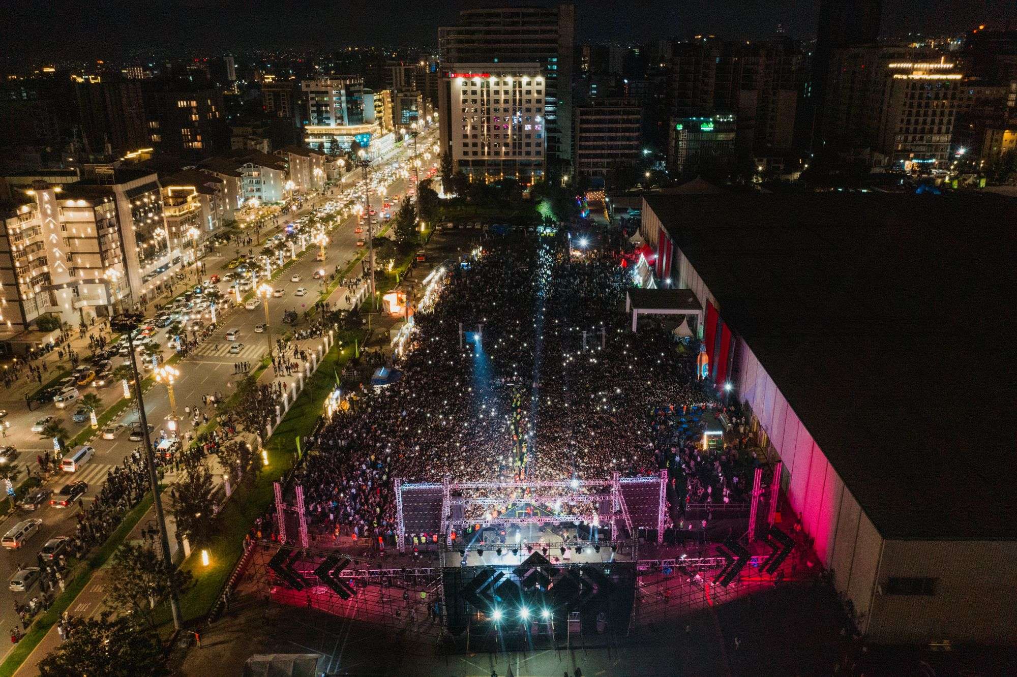 Aerial view of a huge concert crowd facing a lit stage at night